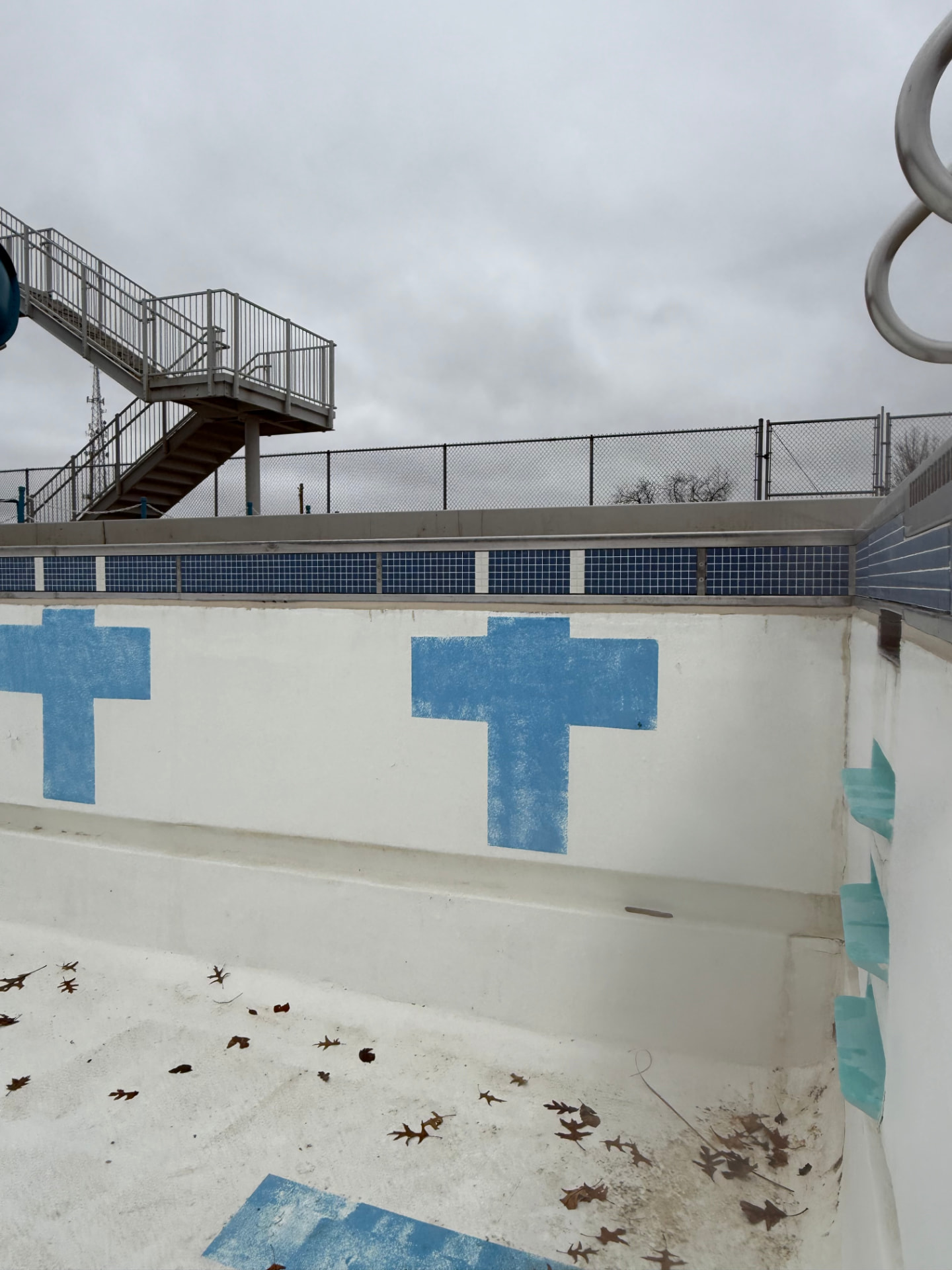 Drained commercial pool basin with painted lane markings and slide staircase
